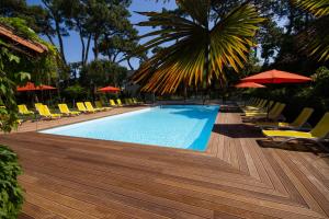 滨海沃Hôtel The Originals Résidence de Rohan (EX RELAIS DU SILENCE)的配有躺椅和遮阳伞的游泳池