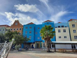 a blue building with a palm tree in front of it at Brion City Hotel BW Signature Collection in Willemstad