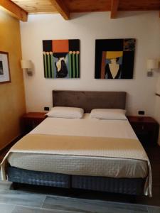 a bedroom with a bed with two paintings on the wall at Villa Mola Bed And Breakfast in Corbara
