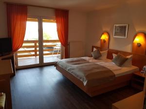 a bedroom with a large bed and a balcony at Land-gut-Hotel Seeblick in Klietz