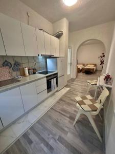 a kitchen with white cabinets and a table and a chair at Apartment Rea Ilidža 2 in Sarajevo