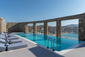 a swimming pool with blue water and windows at Radisson Blu Euphoria Resort, Mykonos in Kalo Livadi