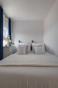uma cama grande com lençóis brancos e almofadas em Apartamenty we Wrocławiu - Jaworska em Breslávia
