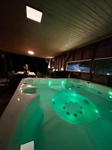 una gran bañera de hidromasaje en una habitación con luz verde en L'échappée Belle by J&J Durbuy Area, en Clavier