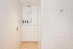 a bathroom with a shower with white tiled walls at Hilton Garden Inn Busselton in Busselton