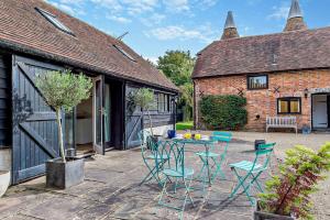 a patio with a table and chairs in a yard at Court Lodge Oast in Heathfield