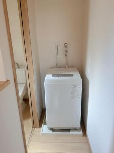 a small white refrigerator in a corner of a room at KANAU in Tokyo