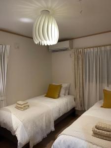 a bedroom with two beds and a chandelier at KANAU in Tokyo