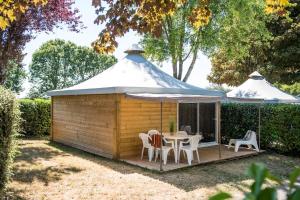 einen Pavillon mit einem Tisch, Stühlen und einem Sonnenschirm in der Unterkunft Parc du Charouzech in Salles-Curan