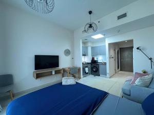 een woonkamer met een blauw bed en een bank bij Warm and Elegant Studio in Dubai in Dubai