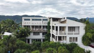a white house with trees and mountains in the background at Akkaw Baler Hometel in Baler