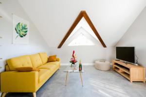 ein Wohnzimmer mit einem gelben Sofa und einem TV in der Unterkunft Kaz Combava in L’Étang-Salé