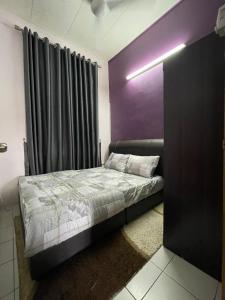 ein Schlafzimmer mit einem Bett mit einer lila Wand in der Unterkunft Homestay MamaTwinz, musslimstay, Parit Buntar in Parit Buntar