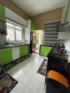 una cucina con armadi verdi e pavimento piastrellato bianco di Homestay MamaTwinz, musslimstay, Parit Buntar a Parit Buntar