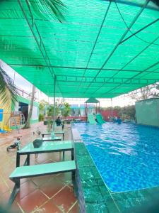 a large swimming pool with a blue roof at Homestay Cô Hai Garden in Ấp Vĩnh Hưng