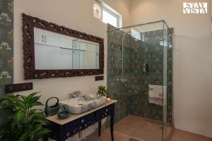 een badkamer met een wastafel en een douche met een spiegel bij StayVista's Indraj Manor - Roman-Inspired Villa with Posh Interiors, Mesmerizing Garden & Outdoor Fireplace in New Delhi