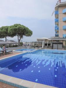 - une piscine avec des carreaux bleus sur le côté d'un bâtiment dans l'établissement Hotel La Bussola, à Lido di Jesolo