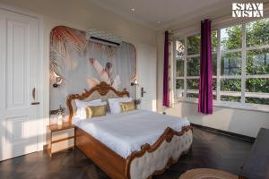 a bedroom with a large bed in a room with windows at StayVista's Indraj Manor - Roman-Inspired Villa with Posh Interiors, Mesmerizing Garden & Outdoor Fireplace in New Delhi