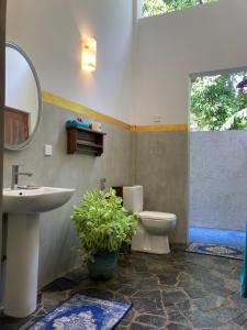 a bathroom with a sink and a toilet and a mirror at Amba Kola Udawalawa in Udawalawe