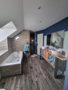 ein großes Badezimmer mit zwei Waschbecken, einer Badewanne und einer Badewanne in der Unterkunft Chambre oiseaux in Larchamp