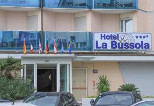 un panneau de l'hôtel la bussola devant un bâtiment dans l'établissement Hotel La Bussola, à Lido di Jesolo