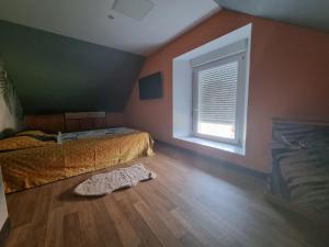 ein Schlafzimmer mit einem Bett, einem Fenster und einem Holzboden in der Unterkunft Chambre oiseaux in Larchamp