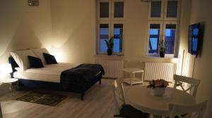 a bedroom with a bed and a table and windows at Apartamenty Street 18 in Toruń