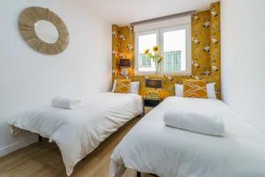 twee bedden in een kamer met een spiegel en een raam bij Bonito apartamento a pocos minutos del centro CLAV- in Málaga