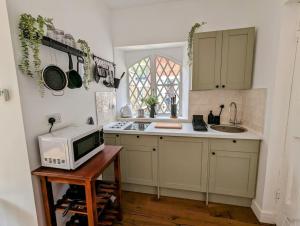 a kitchen with a microwave and a sink and a counter at The Snug at Cefn Tilla Court in Usk