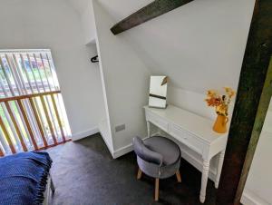 a bedroom with a white desk and a chair at The Snug at Cefn Tilla Court in Usk