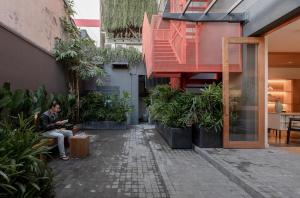 a man sitting on a bench in a courtyard with plants at M Village Hai Bà Trưng in Ho Chi Minh City