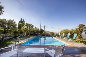 - une piscine dans une villa avec des chaises et une table dans l'établissement L' uliveto, à San Piero Patti