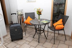 una mesa y sillas con una maleta y una mesa con almohadas de color naranja en Hotel zum Kreuzberg, en Winterberg