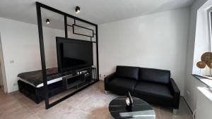 a living room with a black couch and a flat screen tv at Luxus Appartement im Zentrum Düsseldorfs in Düsseldorf