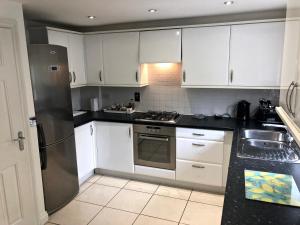 a kitchen with white cabinets and a stainless steel refrigerator at A 3 bedroom townhouse is located in the centre of Newbury in Newbury