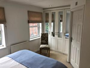 a bedroom with a bed and a chair and windows at A 3 bedroom townhouse is located in the centre of Newbury in Newbury