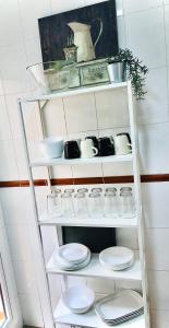 a white shelf with plates and bowls on it at La Terraza del Campo de golf Playa Piscina y parking gratuito in Torre de Benagalbón