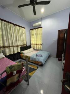 sypialnia z 2 łóżkami i wentylatorem sufitowym w obiekcie Wan Guest House w mieście Pasir Mas