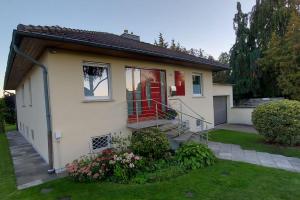 a small white house with a red door at Ferienhaus Distelfink entspannen in der Mitte von Deutschland in Gudensberg