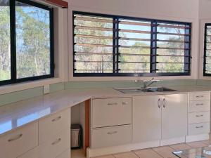een keuken met twee grote ramen en een wastafel bij Lush 2Bedroom Apartment in Yamba Hinterland in Ashby