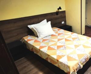 a bed with a quilt on it in a room at Хостел Ритон in Ruse