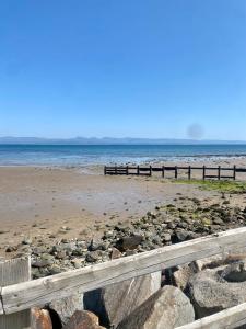 a beach with a fence and the ocean at Hafan Y Môr Caravan - Pwllheli in Chwilog