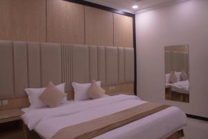 um quarto com uma cama grande e almofadas brancas em منازل الريم (فرع العزيزية) em Riyadh