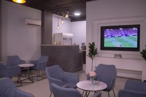 una sala de espera con mesas, sillas y TV en منازل الريم (فرع العزيزية), en Riad