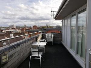 a balcony with chairs and tables on a roof at Pelican House is an exclusive contemporary development in Newbury