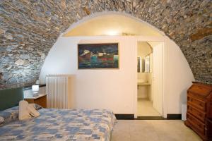 um quarto com uma cama e uma parede de pedra em Dipinti, borgo dei pescatori em Cervo