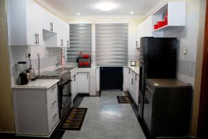 a kitchen with white cabinets and a black refrigerator at The Haven254 in Nakuru