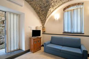 sala de estar con sofá azul y TV en Dipinti, borgo dei pescatori, en Cervo