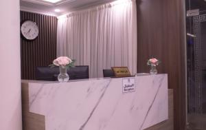 a marble counter with vases of flowers and a clock at منازل الريم للشقق المخدومة فرع العزيزية in Riyadh