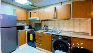 a kitchen with wooden cabinets and a washer and dryer at Rare Holiday Homes - Close to FIVE Hotel - City Skyline View - lavender 1 - R309 - Jumeirah Village Circle in Dubai